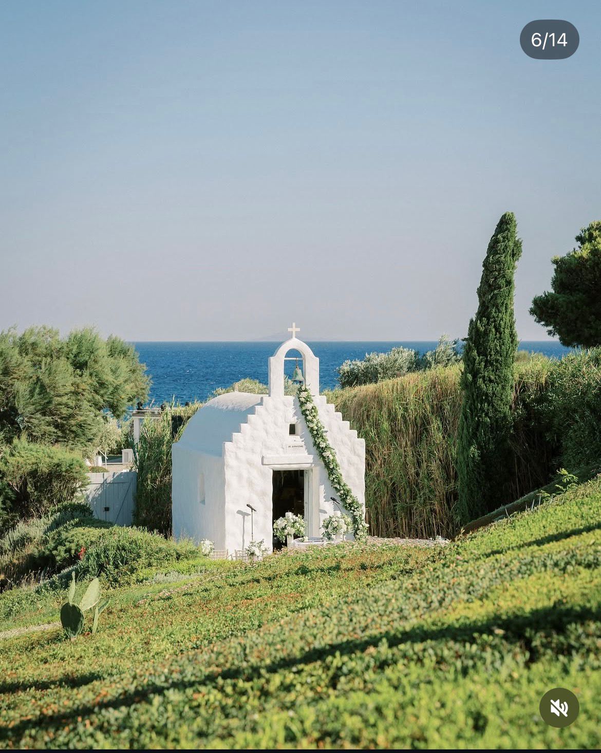 Whitewashed Greek chapel dressed with flowers above the sea