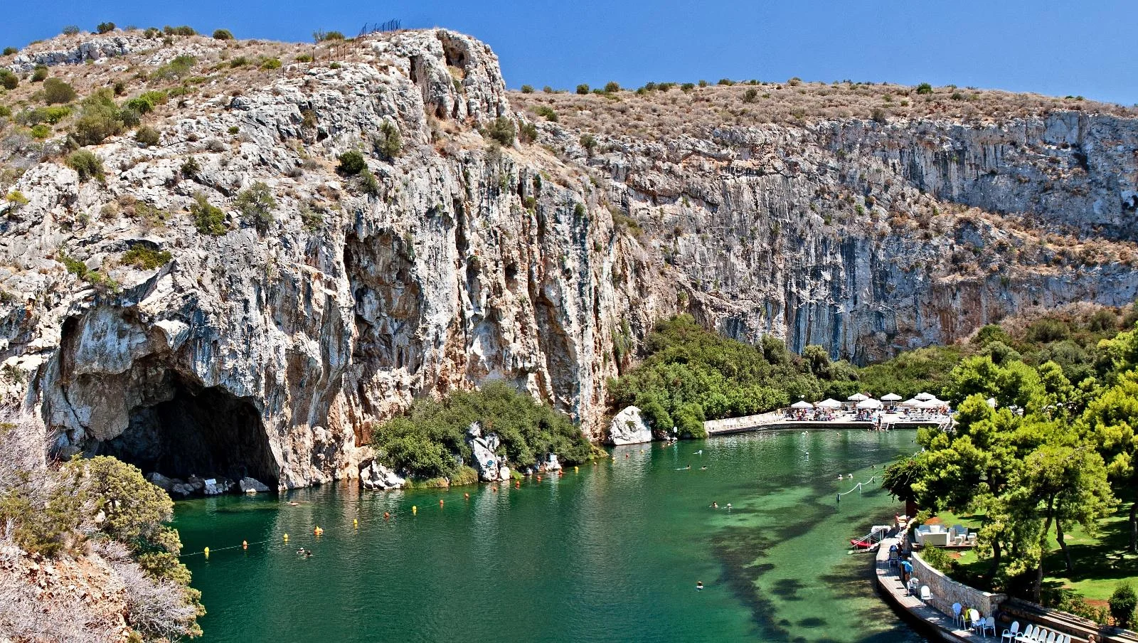 Lake Vouliagmeni framed by rocky cliffs and the blue Aegean coast